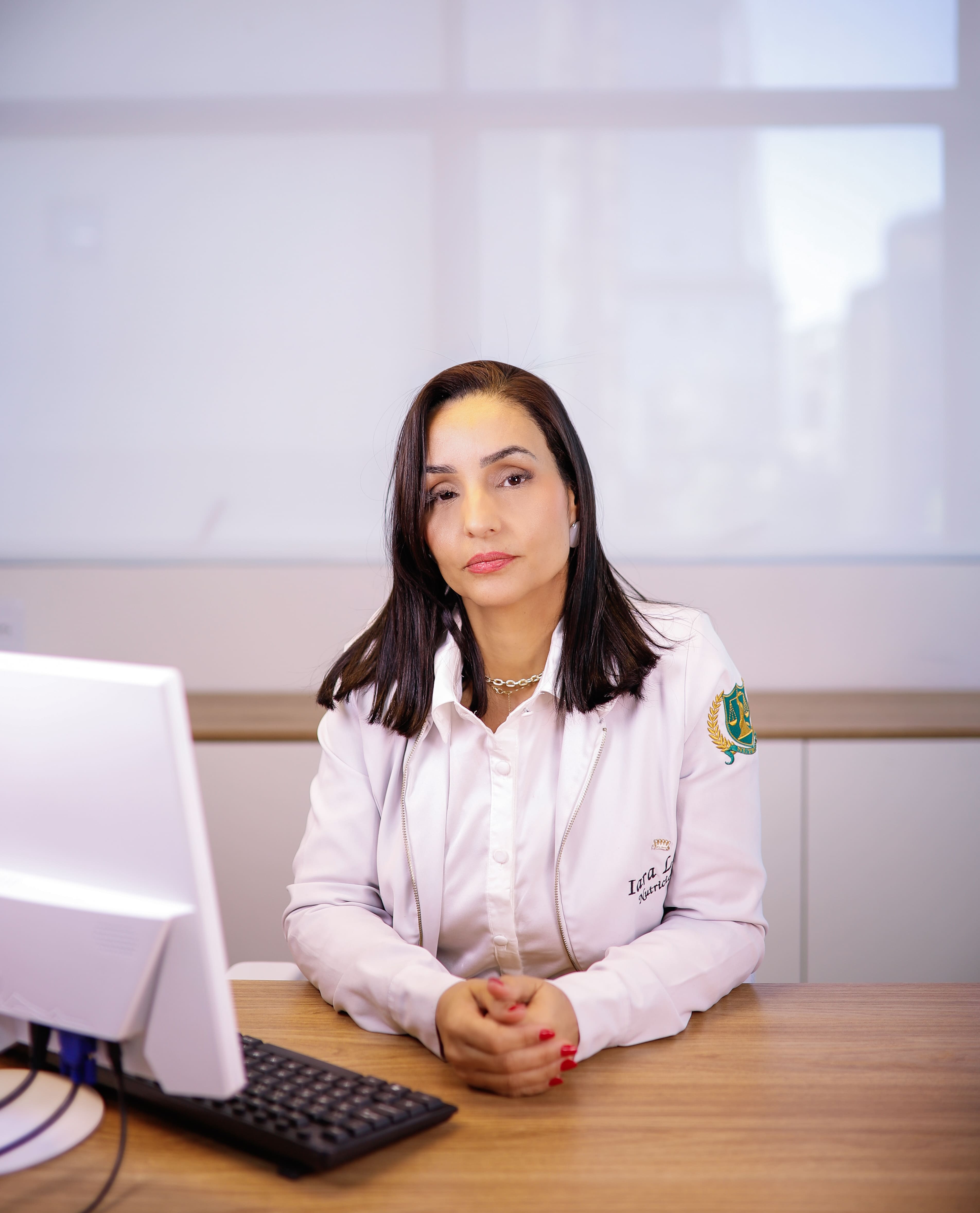Doutora Iara Lelis sentada em sua mesa de atendimento